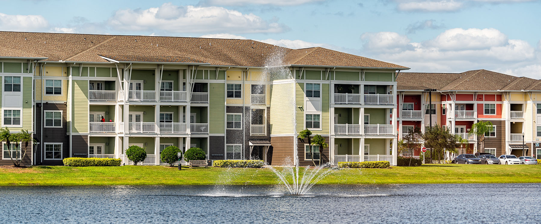 Apartment complex with a lake and fountain in the foreground